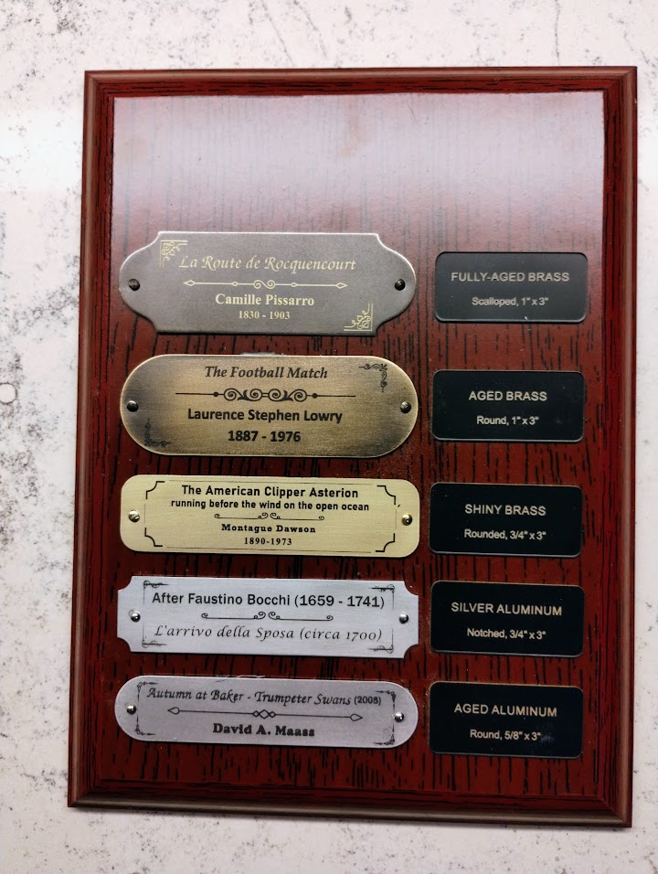 The mounted sample board on a rosewood plaque, five labelled nameplates below a space left for the shop's own nameplate